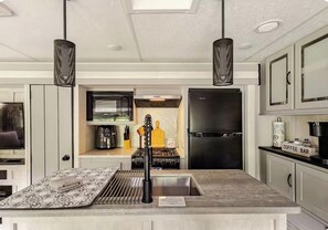 Een moderne keuken met een centraal eiland, een fornuis, een koelkast en hanglampen.