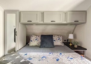 A bedroom with a bed, a bedside table with a lamp, and a door. - Lakeside Hideaway with Romantic Vibes! Boat dock-boardwalk. Private boat launch. (Newport)