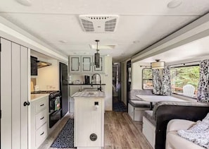 Un intérieur de camping-car compact comprenant un coin cuisine, un espace repas et un coin salon.