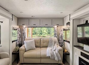 A cozy interior with a sofa, curtains, and a television. - Lakeside Hideaway with Romantic Vibes! Boat dock-boardwalk. Private boat launch. (Newport)