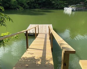 Une jetée en bois s’étendant dans une étendue d’eau, avec un bateau amarré sur la droite.