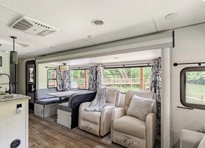 Helles Wohnmobil-Interieur mit Essbereich, Sitzgelegenheiten und einem Fenster mit Aussicht.