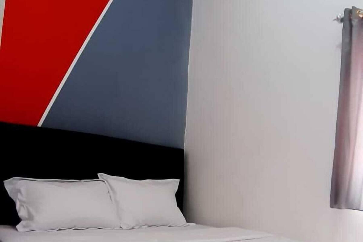 Ein ordentlich bezogenes Bett mit weißer Bettwäsche in einem Zimmer mit geometrischem Wanddesign.