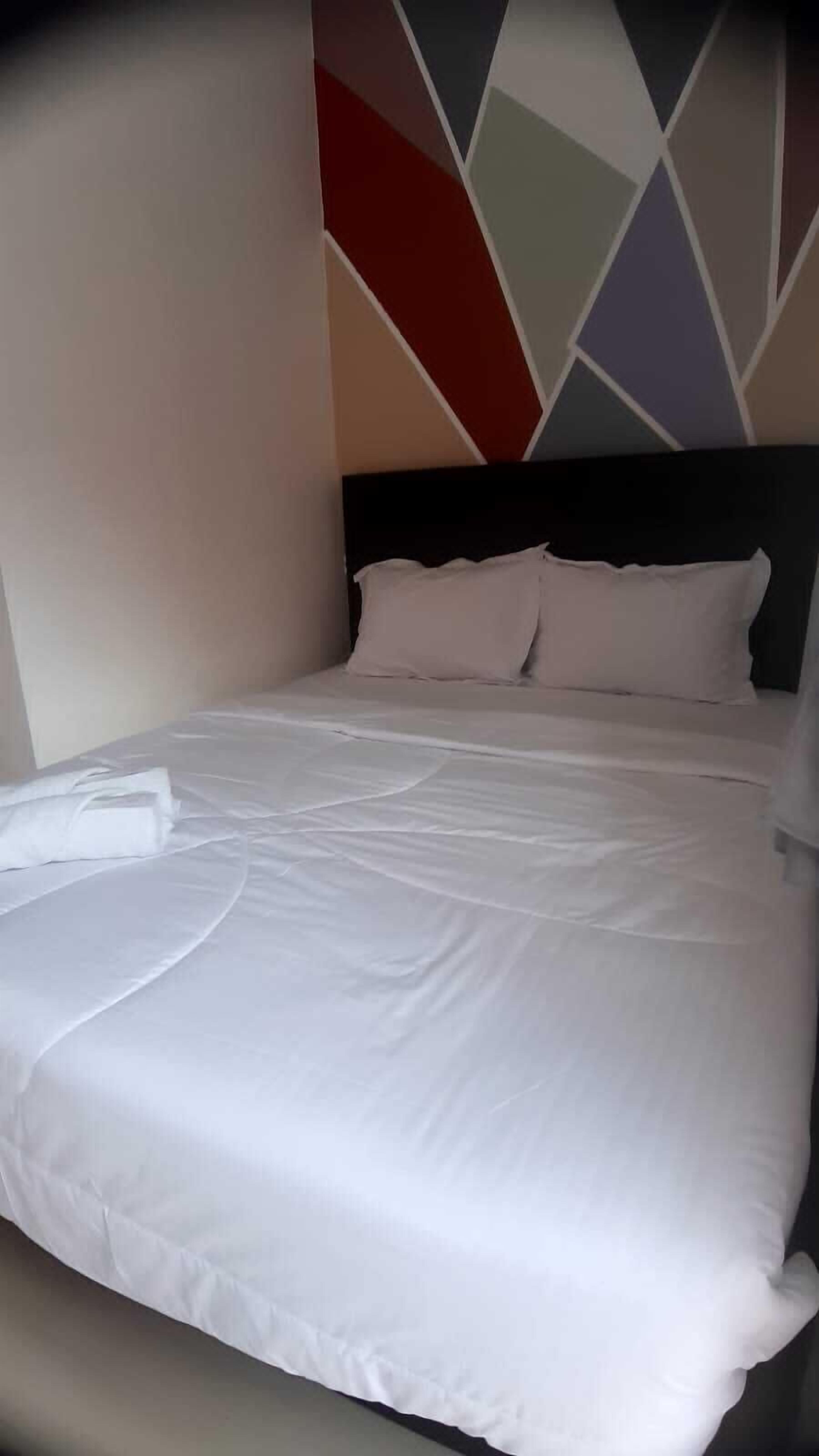 A neatly made bed with white linens in a hotel room.