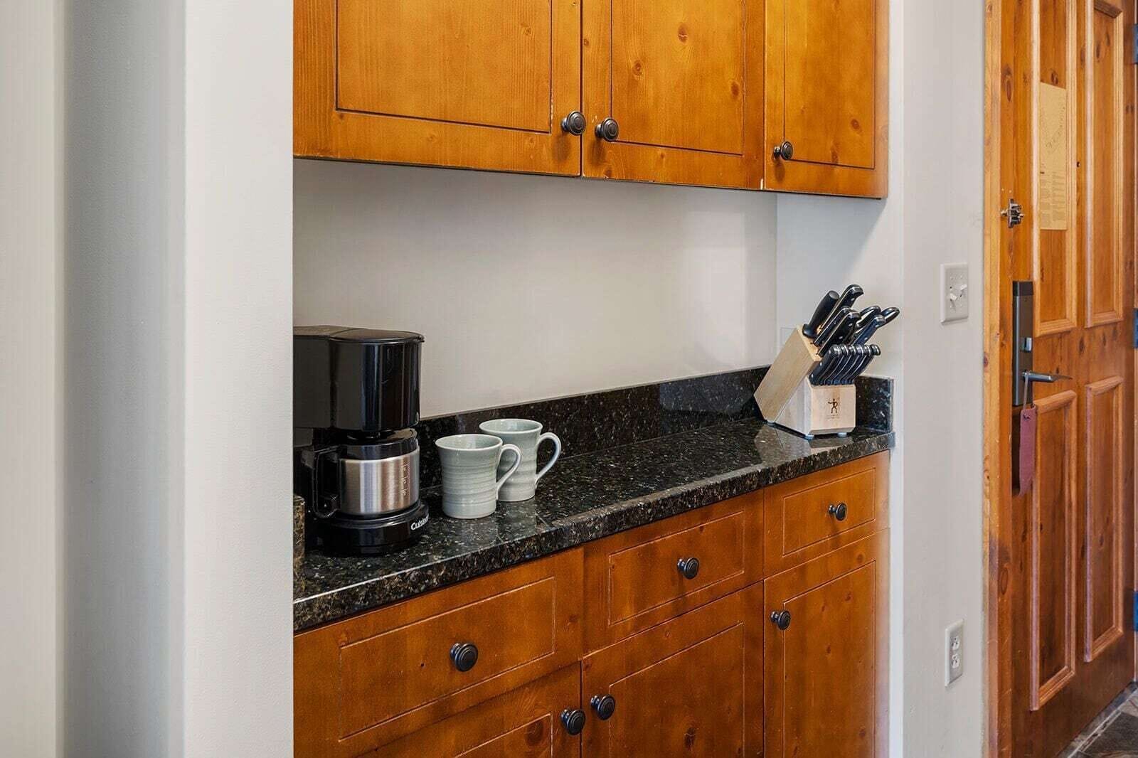 Eine Küche mit Holzausstattung, einer Kaffeemaschine und einem Messerblock auf der Arbeitsplatte.