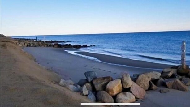 Une plage bordée d’une côte rocheuse, offrant une vue dégagée sur l’océan.