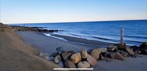 A beach with a rocky shoreline and a clear view of the ocean. - 3 bedroom home in Salt Air Village (Dennis Port)