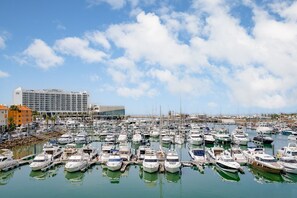 Ein Yachthafen mit vielen vertäuten Booten, ein großes Hotelgebäude und ein klarer Himmel.