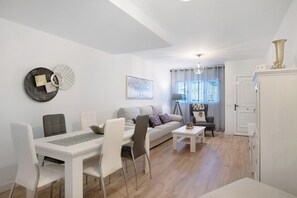 A modern living room with a dining table, chairs, a sofa, a coffee table, and a TV.