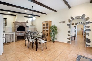Una cocina con horno de ladrillo, mesa, sillas y un armario.
