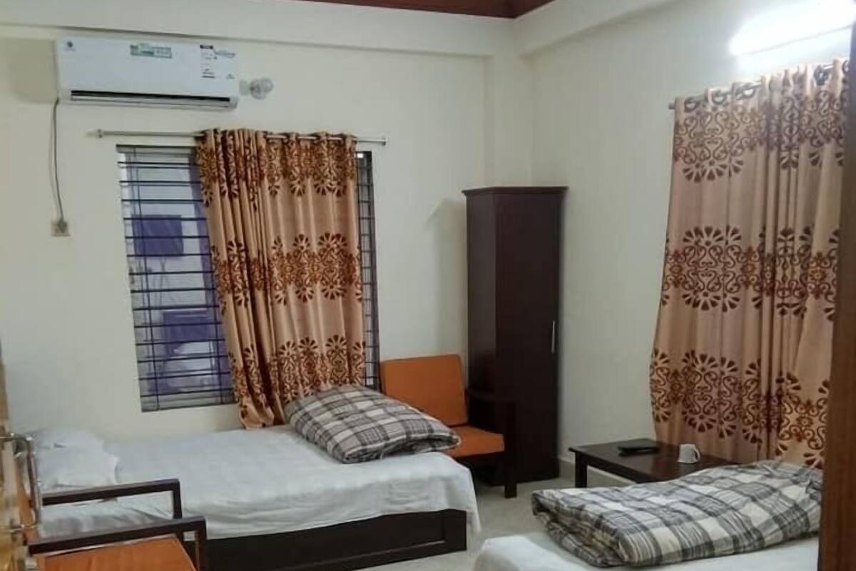 A bedroom with two beds, a wardrobe, and an air conditioning unit.