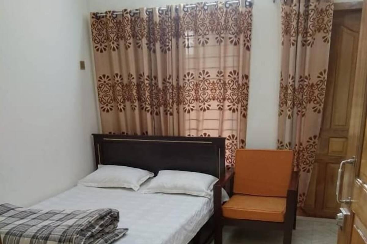A bedroom with a bed, a chair, a bench, and curtains.