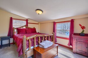 Ein Schlafzimmer mit einem hölzernen Bett, einem Nachttisch, einer Kommode und einem Fenster mit roten Vorhängen.