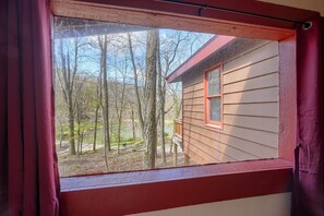 Ein Fenster mit Blick auf eine Holzhütte und die umliegenden Bäume.