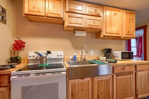 A kitchen with wooden cabinets, a stove, a sink, and a microwave.