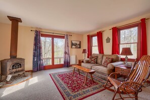 Ein gemütliches Wohnzimmer mit Kamin, einer Couch, einem Schaukelstuhl und einem gemusterten Teppich.