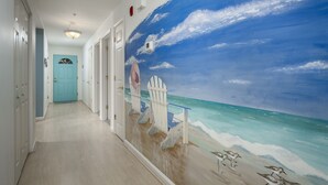 A hallway with a beach mural, white doors, and a blue door at the end.
