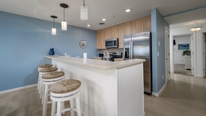 A modern kitchen with a central island, bar stools, and stainless steel appliances.