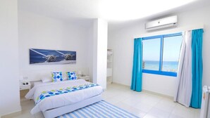 Una camera da letto moderna con un grande letto, vista sul mare attraverso una finestra e un quadro raffigurante una barca a vela.