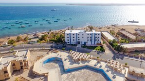 Vista aerea di un hotel sulla costa con piscina, accesso alla spiaggia e vista sul mare.