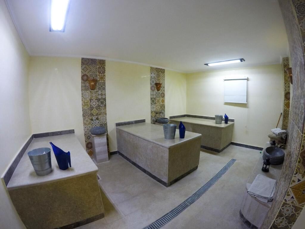 A hotel bathroom with three sinks, a mirror, and a towel rack.