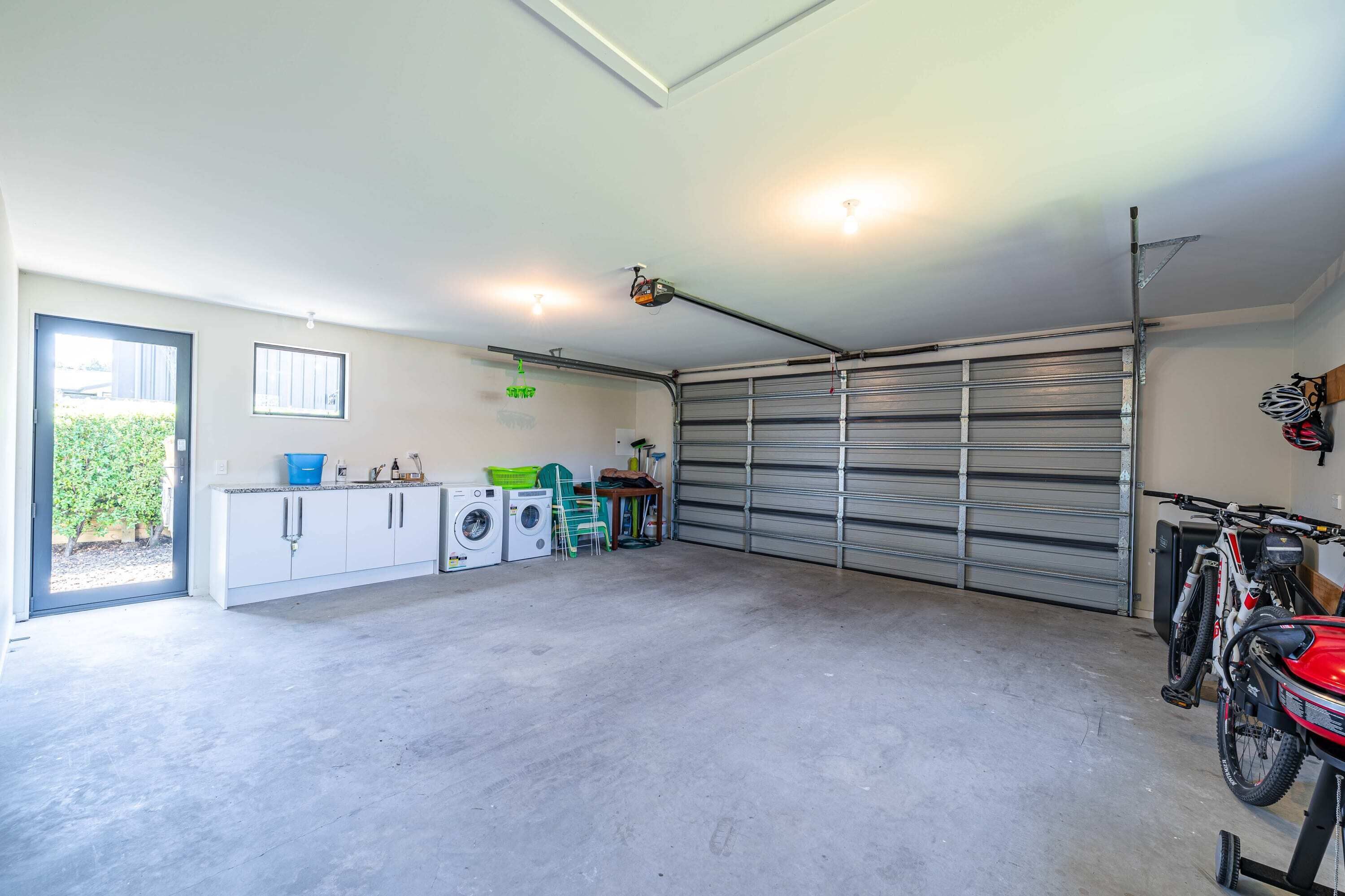 A garage with a washing machine, a bicycle, and a motorcycle.