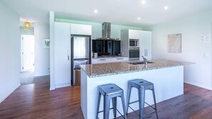 A modern kitchen with a central island, stainless steel appliances, and a bright, open layout. - Hoheria Mountain Lodge (Wānaka)