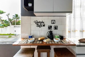 Eine Küche mit gefliestem Rückspritzschutz, einer Kaffeemaschine und einem Tisch, der mit Frühstücksartikeln gedeckt ist.