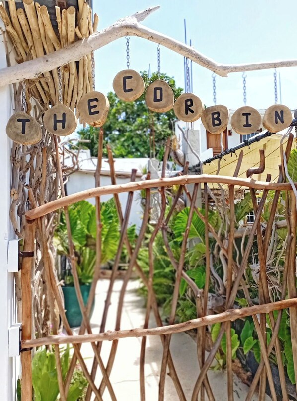 Une porte surmontée de lettres en bois formant le mot « THE CORBIN » et une clôture en osier.