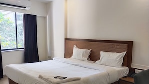 A hotel room with a large bed, a ceiling fan, a window with curtains, and a bedside table with a lamp. - Hotel Ace Residency (Mumbai)