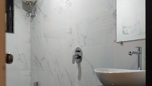 A bathroom with a white marble wall, a white sink, and a shower. - Hotel Ace Residency (Mumbai)