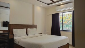 A hotel room with a bed, a desk, a chair, a TV, and a window with curtains. - Hotel Ace Residency (Mumbai)