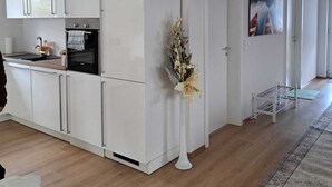 A modern kitchen with white cabinets, a built-in oven, and a small countertop. - Ferienwohnung Direkt in Wehrheim (Wehrheim)