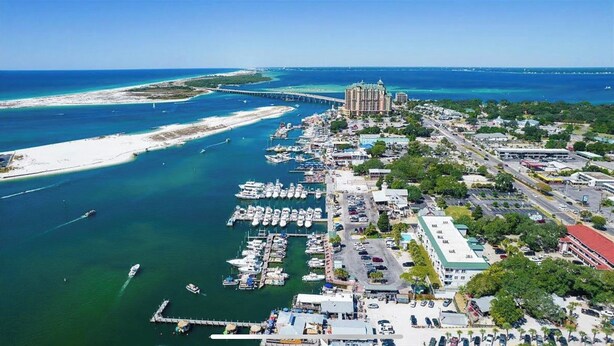 An aerial view of a coastal town with a marina, a large hotel, and a bridge connecting to a peninsula. - Harbor Central Penthouse (Destin)