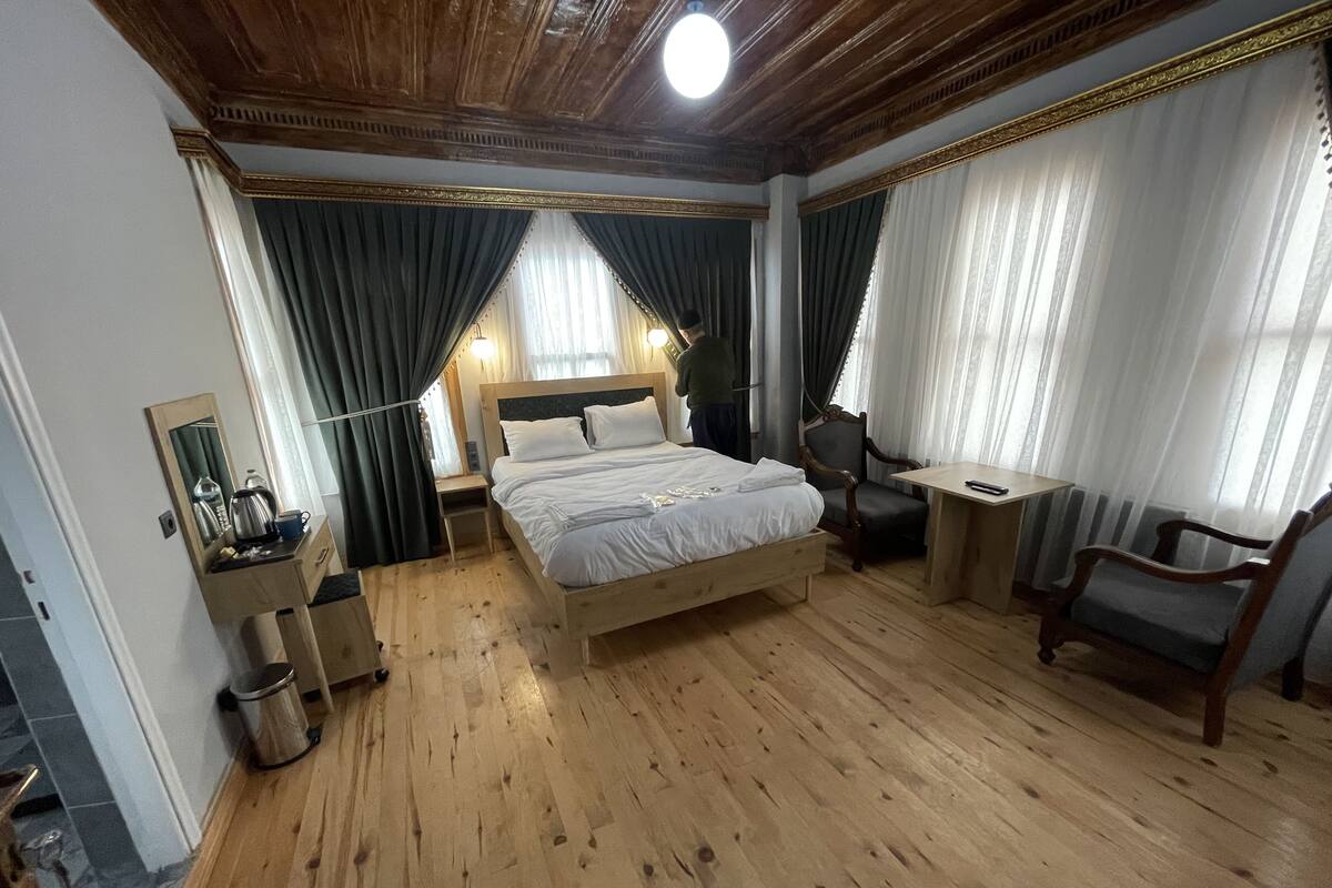 Ein Schlafzimmer mit einem hölzernen Bett, Nachttischen, einem Sessel und einem Schreibtisch.