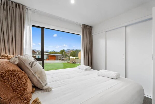 A hotel room with a large bed, a view of the outdoors, and a sliding door.
