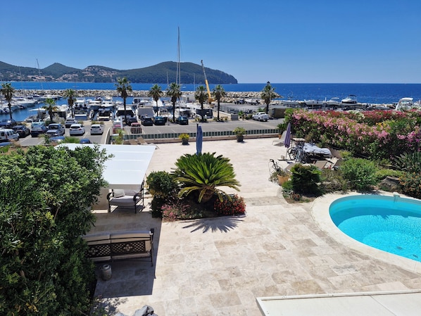 A marina with boats, a swimming pool, and a view of the sea.
