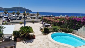 Zona de piscina amb vista al mar i vaixells amarrats.