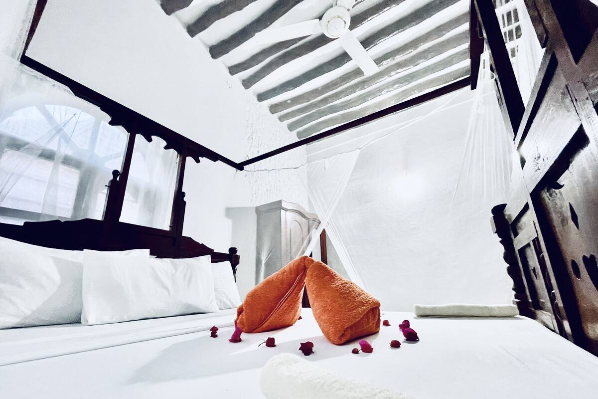 Une chambre à coucher avec un lit, une fenêtre et un ventilateur de plafond.
