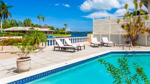 A pool area with lounge chairs, a pool, and a view of the water. - Private Luxury Waterfront Villa with Pool (West Bay)