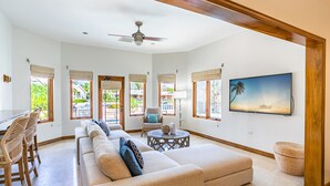 A spacious living room with a large beige sofa, a wooden coffee table, and a television on the wall. - Private Luxury Waterfront Villa with Pool (West Bay)