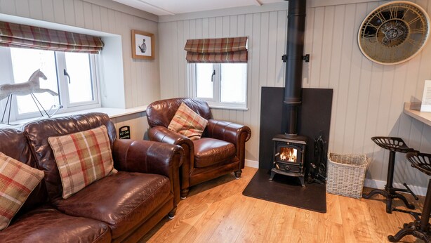 A cozy living room with leather sofas, a fireplace, and a clock on the wall. - Grouse Lodge (Scarborough)
