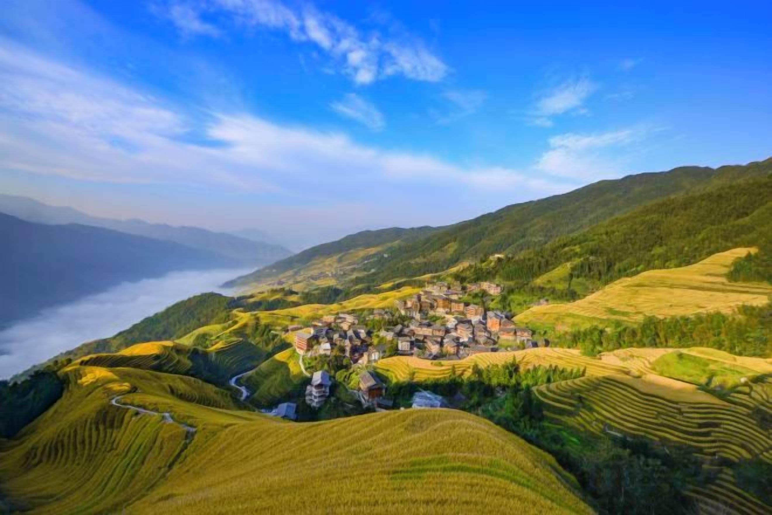 Un paisaje escalonado con un pueblo y una masa de agua al fondo.