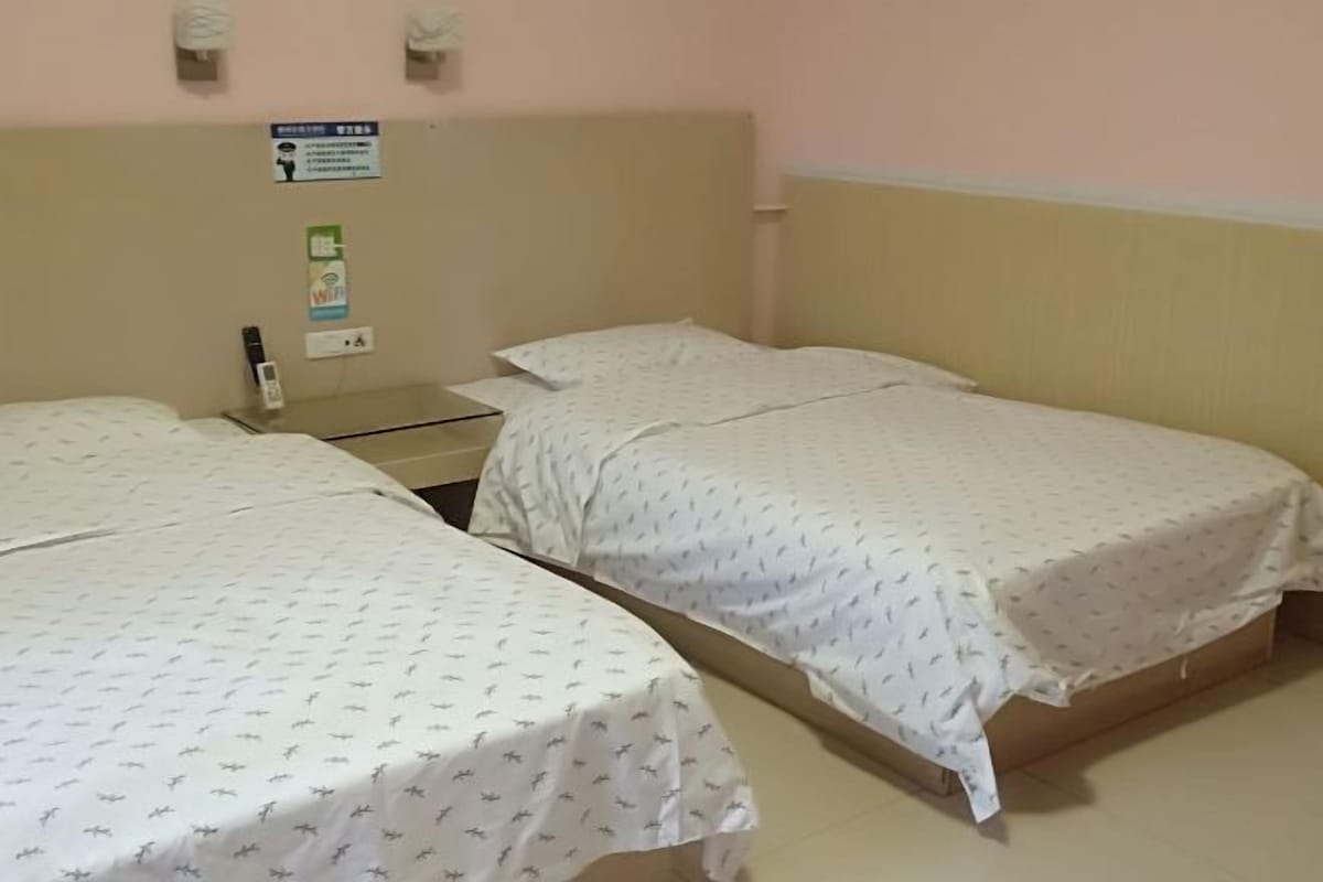Ein Zimmer mit zwei Einzelbetten, einem Nachttisch mit Lampe sowie einer Wandleuchte.