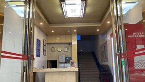 Zona de recepción con mostrador, reloj y escalera que sube a otro nivel.