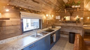 A rustic kitchen with wooden walls, a marble countertop, and blue cabinets.