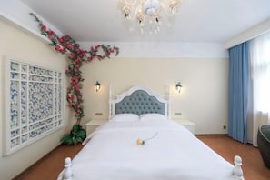 A neatly made bed with a single rose, a chandelier, a wall-mounted light fixture, and a decorative plant. - Jindalai Tianyuan Hotel (Xing'an County)