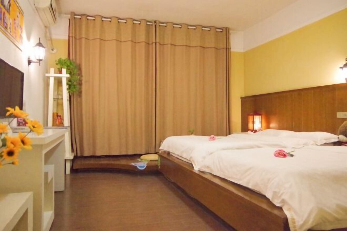 Een hotelkamer met een bed, nachtkastje, lamp en gordijn.