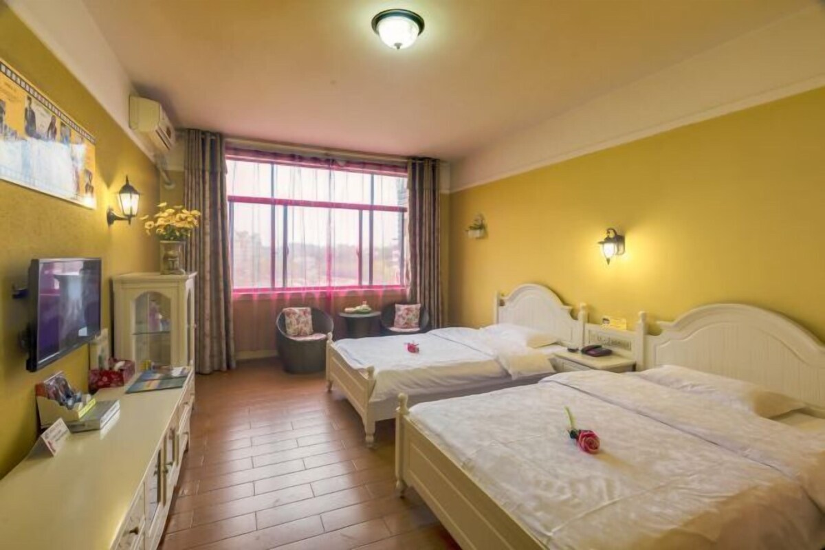 Een hotelkamer met twee bedden, een televisie, een bureau met een computer en een raam met gordijnen.