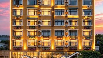 A multi-story hotel with balconies, air conditioning units, and a well-lit facade.